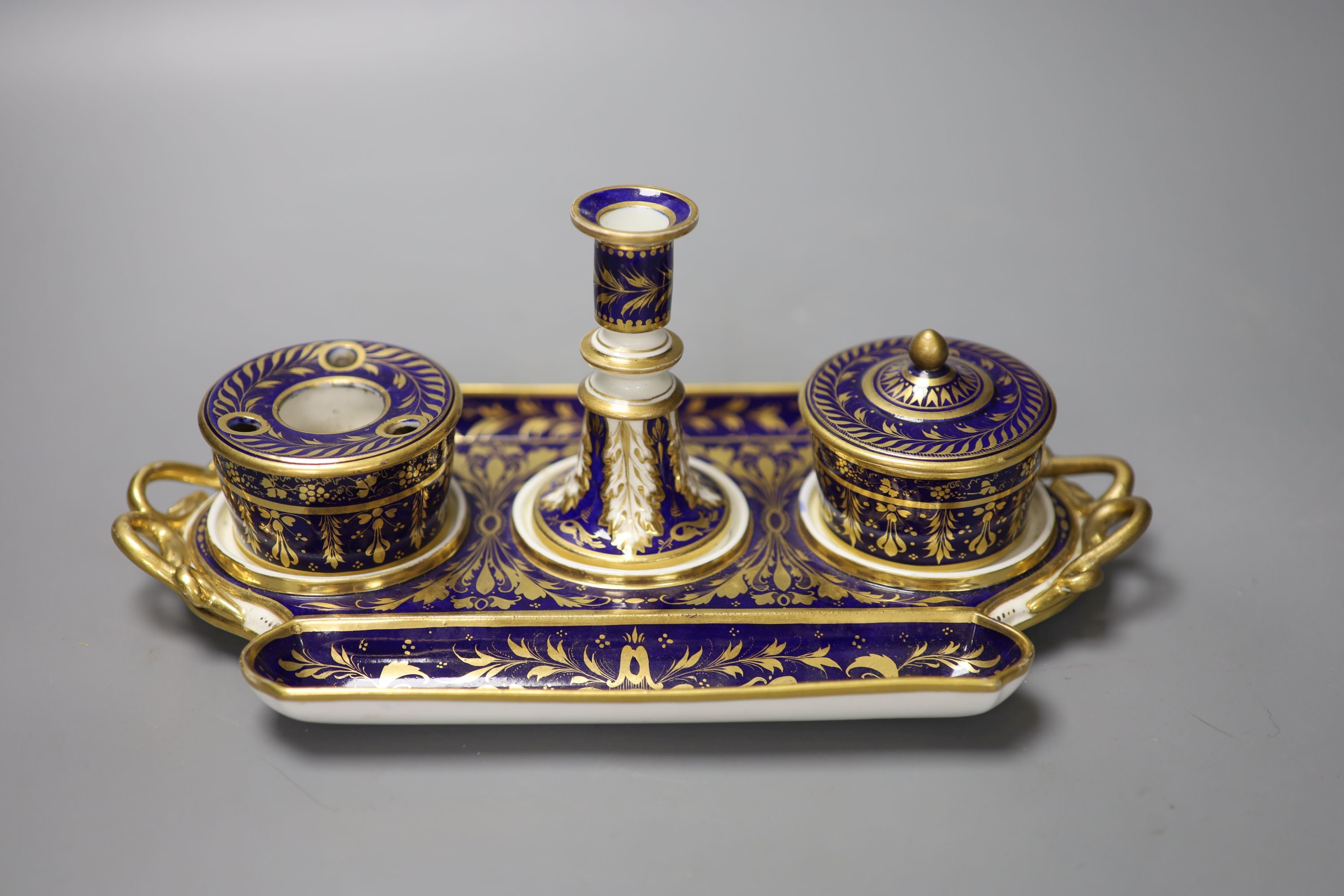 A Derby inkstand ornately gilded on a cobalt blue ground having a sander and cover, inkpot and taper stick, red marks, width 27cm